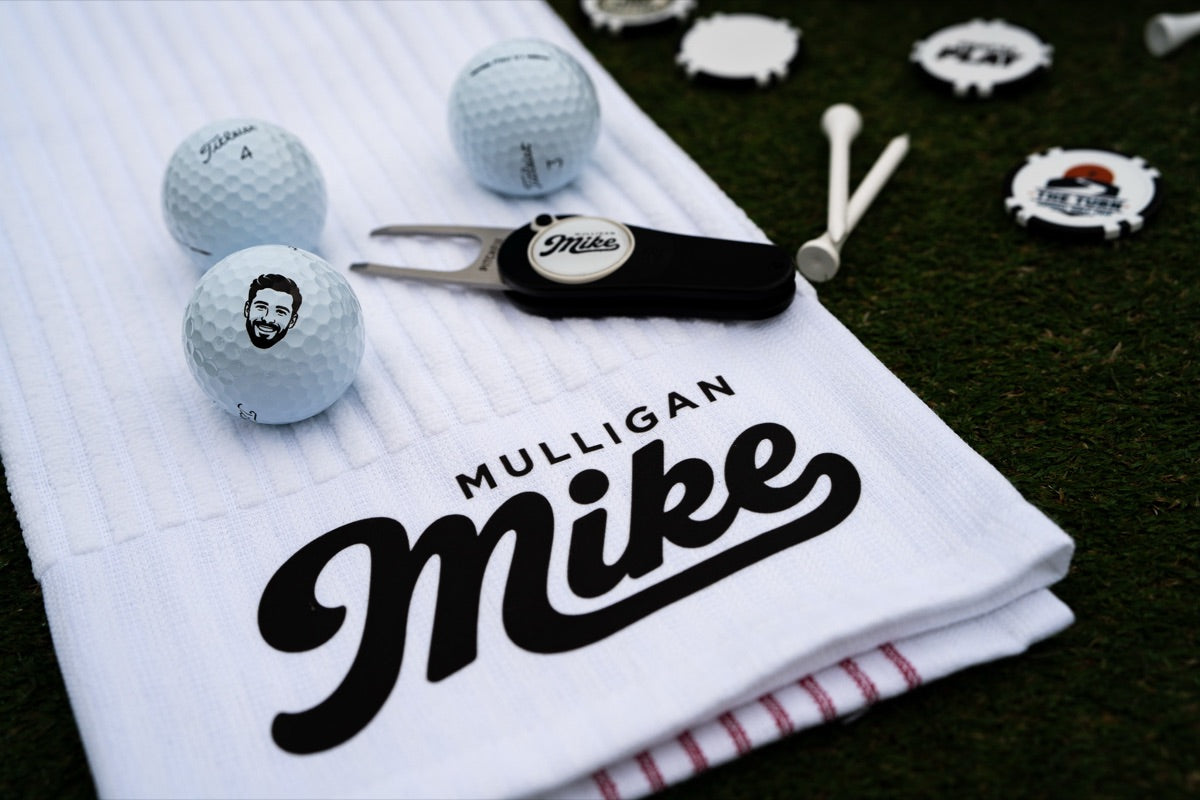 Custom Mulligan Mike golf towel, divot tool and face-printed golf balls on the grass